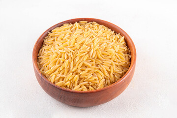 Raw uncooked orzo pasta, Italian dry pasta risoni orzo in bowl on table, copy space