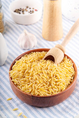 Raw uncooked orzo pasta, Italian dry pasta risoni orzo in bowl on table, copy space