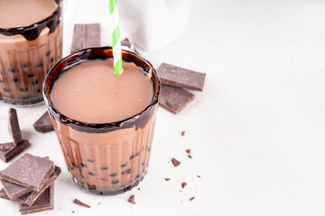 Tasty hot chocolate bubble tea. Cocoa hot or cold beverage with with tapioca balls and dark chocolate syrup, sweet dessert drink on white table with crushed chocolate 