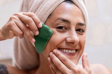 Woman using jade stone tool for beauty routine