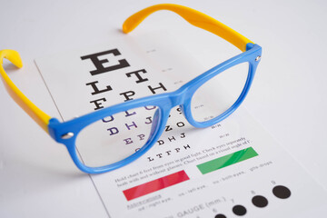 Glasses on eye exam chart to test eyesight accuracy of reading.