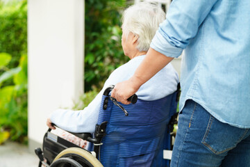 Caregiver help Asian elderly woman disability patient sitting on wheelchair in hospital.