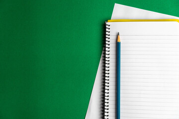 Blank notebook and a calendar Working table with keyboard and notepad, pen, pencil and plant in...