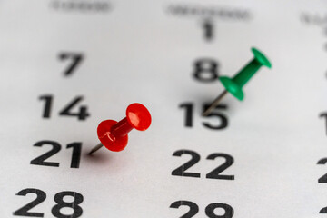 Push-pin in calendar with a blank notebook and pencil kept on a world map to decide date and...