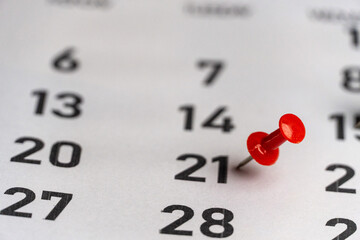 Push-pin in calendar with a blank notebook and pencil kept on a world map to decide date and...