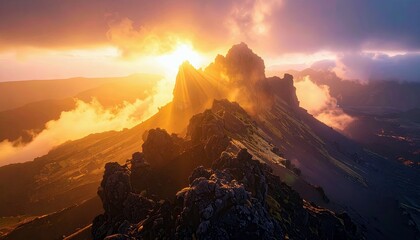 A majestic mountain range is bathed in the warm, golden light of a dramatic sunset, with sunbeams breaking through clouds and mist over jagged peaks.