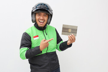 Excited asian online taxi driver holding and pointing Indonesian vehicle registration certificate