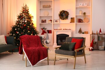 Fireplace, armchairs, Christmas tree and festive decor in stylish room