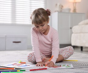 Cute little girl drawing with felt pen on floor at home