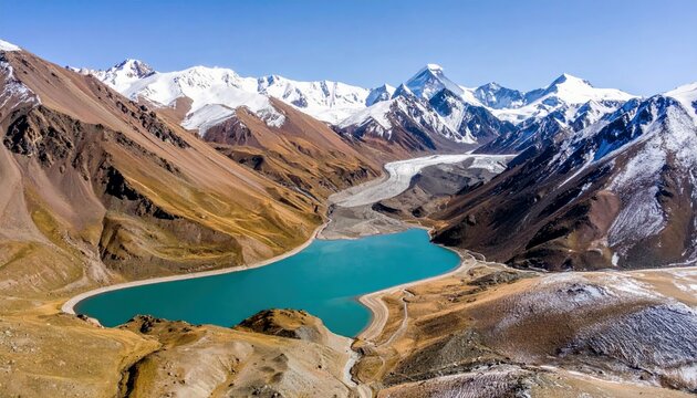 A stunning aerial view of a vibrant turquoise lake in a mountain valley, surrounded by brown, arid slopes and majestic snow-covered mountains.