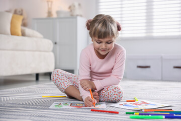 Cute little girl drawing with felt pen on floor at home