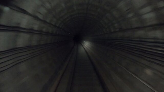 Subway train moving fast at dark tunnel. Speed underground train riding in tunnel. Urban metro driving belowground. Point of view from the railway cabin. Transportation of people concept. Time lapse