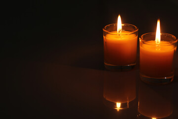 A candle burned on a glass holder in the dark, a symbol of hope.