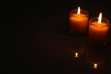 A candle burned on a glass holder in the dark, a symbol of hope.