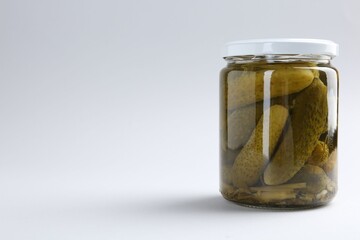 Pickled cucumbers in jar on light background. Space for text