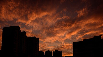 Sunset urban silhouette city skyline with orange sky and glowing sun creating dramatic dusk scenery, showing buildings, horizon, warm light, shadows and vibrant atmosphere over the modern landscape