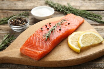 Piece of salmon fillet, spices and lemon on wooden table, closeup