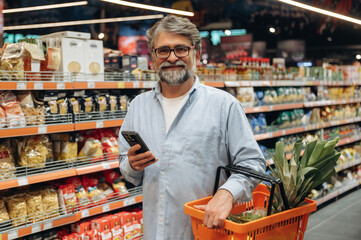 With big pineapple. A senior man is buying food in the grocery store