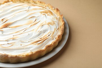Delicious meringue pie on light brown table, closeup. Space for text