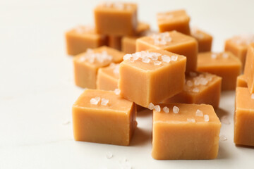 Tasty caramel candies with salt on light table, closeup. Space for text