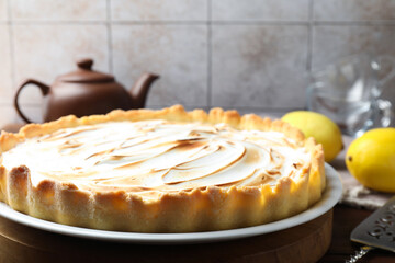 Tasty lemon meringue tart, server and fruits on wooden table, closeup. Space for text