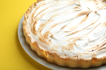 Tasty lemon meringue tart on yellow background, closeup