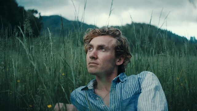 Young man lying alone in the grass, reflecting on life in nature's embrace