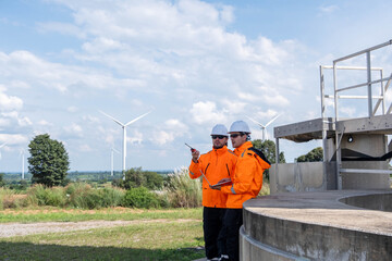 Workers monitor wind energy production at a renewable energy site during a sunny afternoon