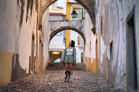 Woman with her dog exploring an archway in Evora