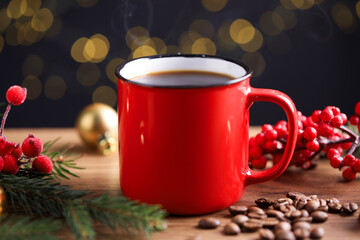 Aromatic coffee in red mug, beans, berries and fir tree branches on wooden table against black background with blurred lights, closeup. Christmas greeting card