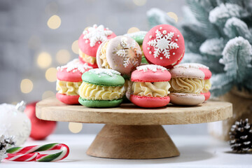 Tasty macarons and Christmas decor on white table against blurred lights