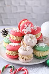 Tasty Christmas macarons and festive decor on light table, closeup