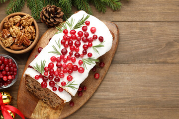 Tasty Christmas cake with icing, cranberries, rosemary and festive decor on wooden table, flat lay. Space for text