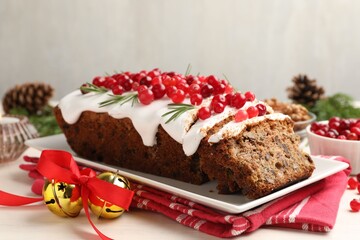 Tasty Christmas cake with icing, cranberries and rosemary on white wooden table, closeup