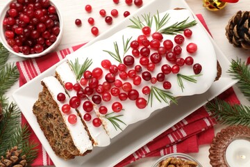 Tasty Christmas cake with icing, cranberries, rosemary and festive decor on white wooden table, flat lay