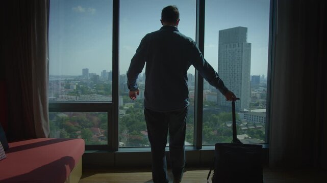 A thoughtful and contemplative man gazes at the beautiful city skyline from a highrise window