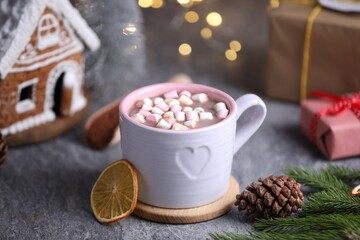 Tasty cocoa with marshmallows and Christmas decor on grey table against blurred lights, closeup