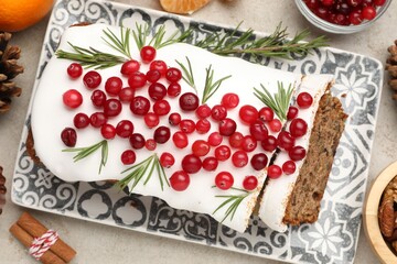 Tasty Christmas cake with icing, cranberries and festive decor on light grey table, flat lay