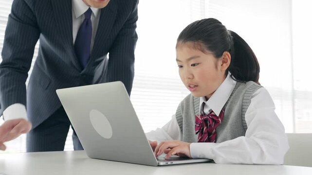 女の子にパソコンの使い方を指導する男性教師