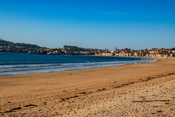 Sandy Beach with Coastal Town Under a Clear Blue Sky