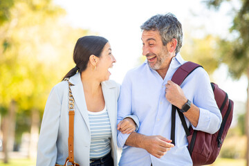 Excited couple laughing and linking arms while walking outdoors