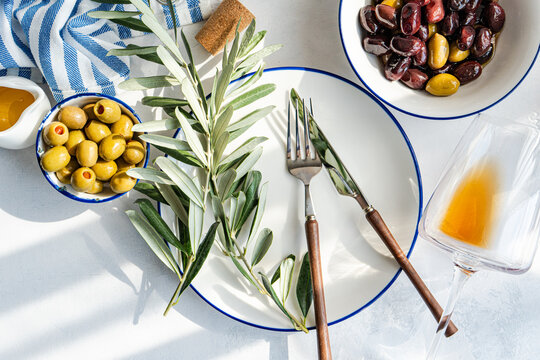 Top view of Greek olives, amber wine, and table setting