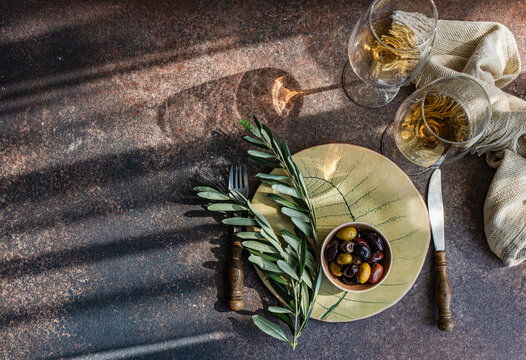 Top view of Greek olives and amber wine on rustic table