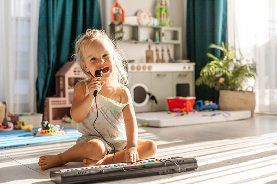 Toddler girl playing piano and singing with microphone