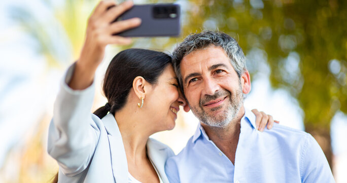 Close-up of a loving couple taking a selfie outdoors with joyful expressions - Powered by Adobe