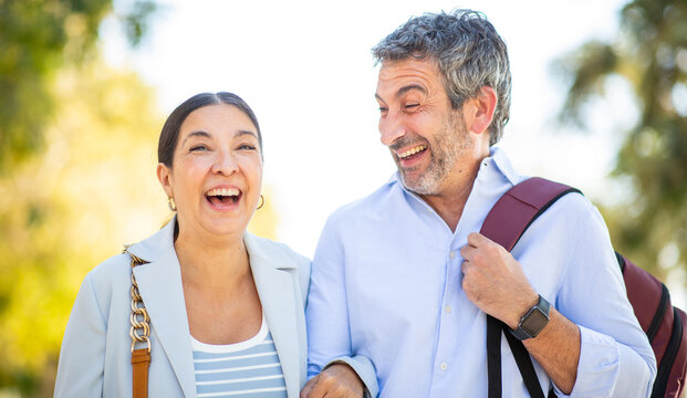 Cheerful couple laughing together while walking on a sunny path outdoors - Powered by Adobe