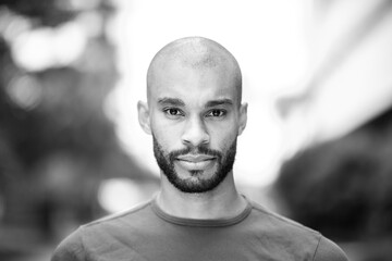 Serious man with beard wearing casual t-shirt in black and white portrait outdoors