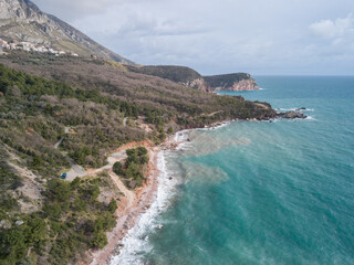 A blue camper van at the shore near Sveti Stefan island, Montenegro, drone shot
