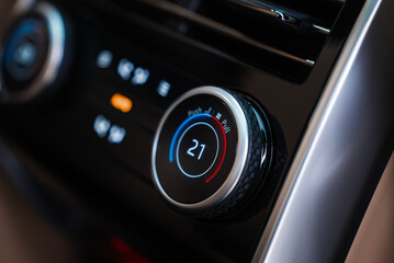 Obraz premium Close up focuses on a climate control dial set to 21C, blue to red ring, soft touch black trim, metallic bezel, and icons, shallow depth of field, glossy reflections.