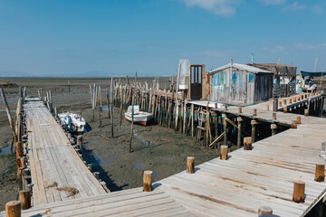 Wooden piers extend over dry sea bed under a clear sky